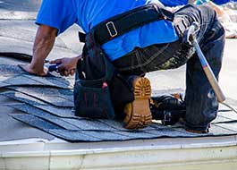 aq contracting worker wearing blue shirt on top of roof installing shingles