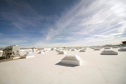 white, TPO rooftop with flat roof installation and generators under blue sky